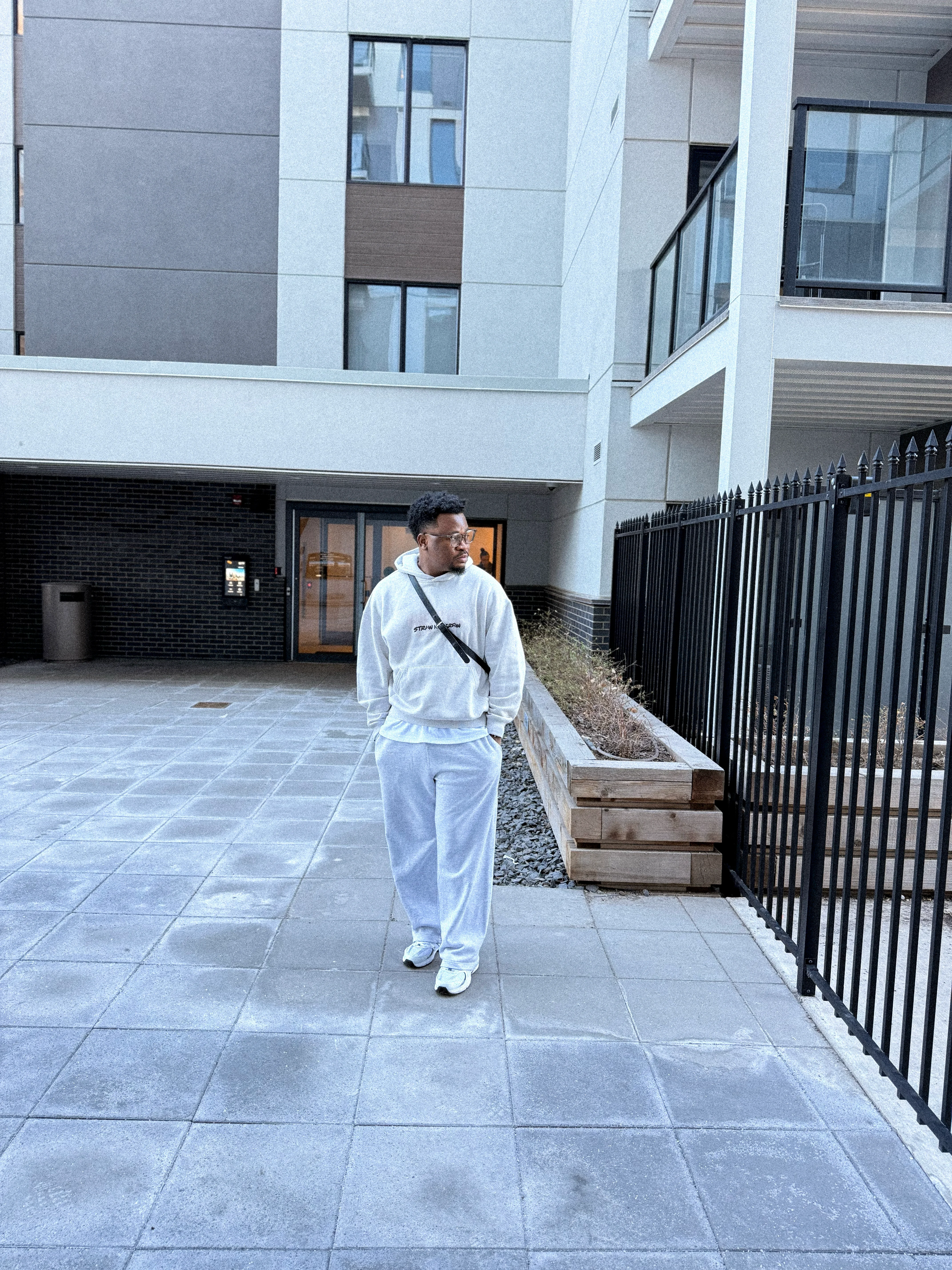 Oluwayemi walking across a paved courtyard between apartment blocks in the late afternoon
